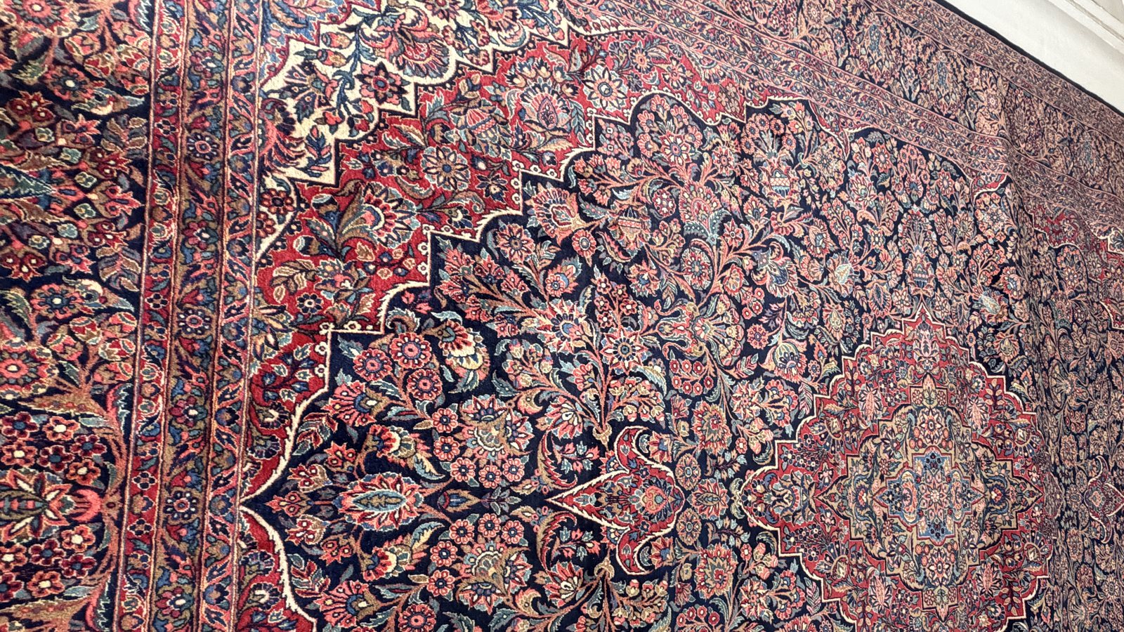 A rug photographed flat after water-damage recovery, field colour brought back through the pile